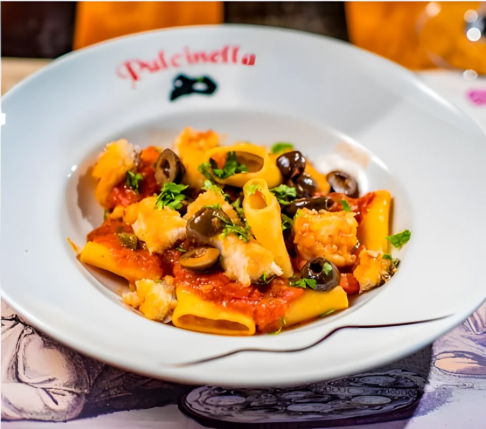 Paccheri con salsa de tomate y aceitunas en un plato de Pulcinella
